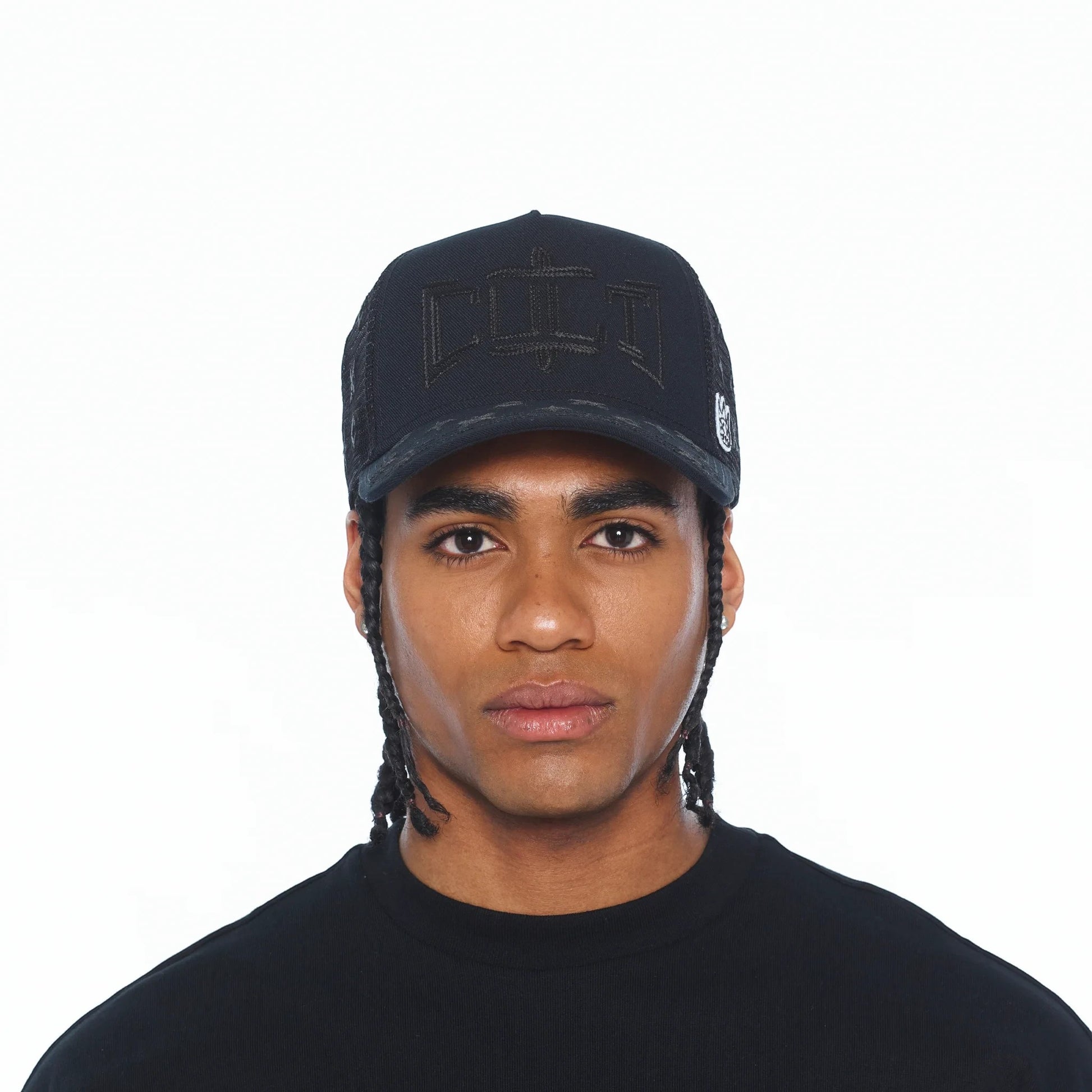 A man wearing a black Ballers Clothing Shop mesh back trucker hat with a rope detail and embroidered front logo.