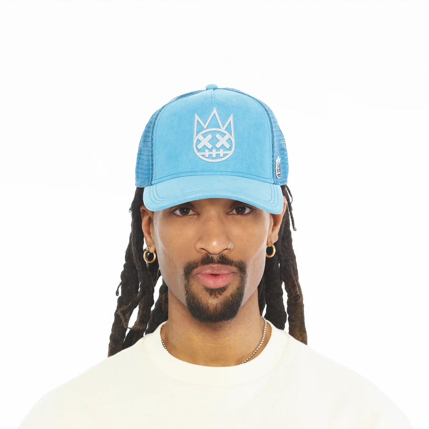Ballers Clothing Shop Navagio Bay blue suede trucker hat with mesh back and white chain-stitch logo on a male model