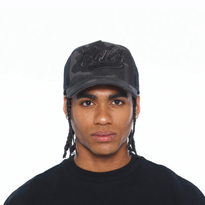 Ballers Clothing Shop camo mesh back trucker hat with black crystal script logo worn by a man