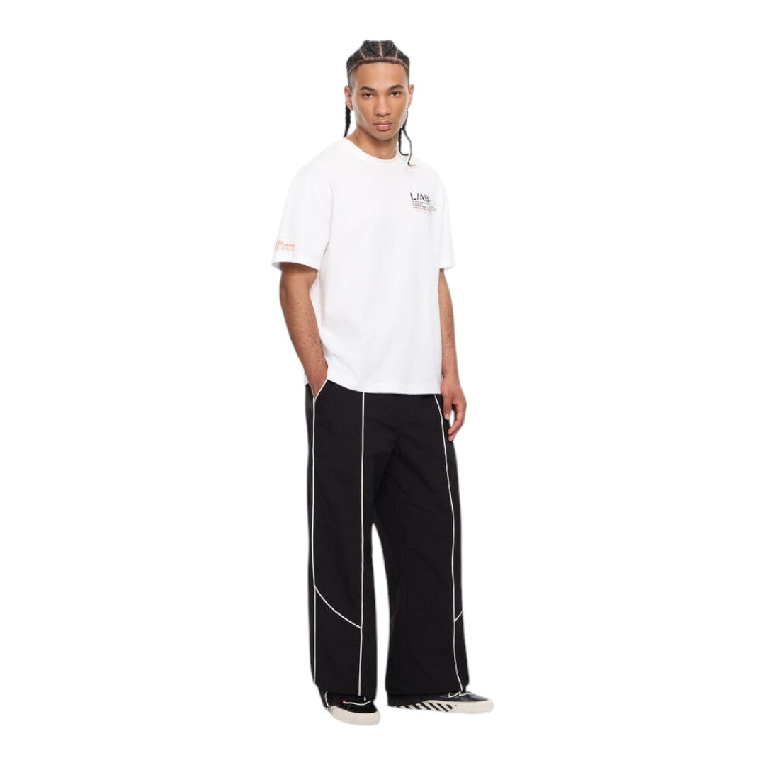 Ballers Clothing Shop model wearing a white L/AB c/o Off-White cotton t-shirt with orange sleeve logos and black pants.